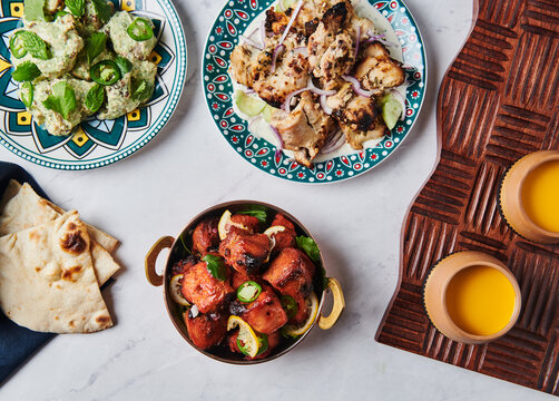 Table setting with chicken Bihari Kebab, Chicken Tikka Kebab, and Mango Lassi 