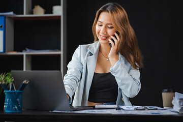Young asian businesswoman beautiful charming smiling and talking on the mobile phone in the office.
