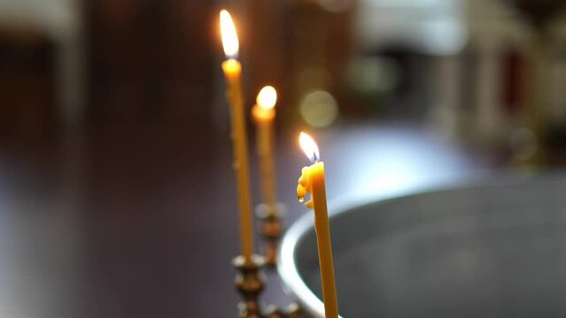 three burning candles on the font for baptism in the Orthodox Church.