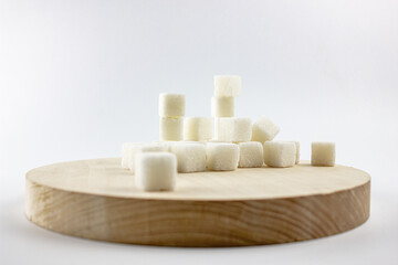 Sugar on a wooden saucer. Wooden plate with sugar cubes on a white background.
