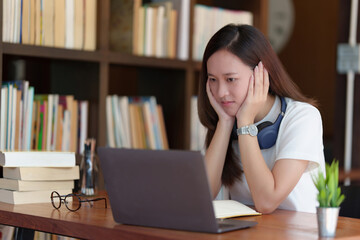 Back to school concept. Young college woman using laptop at library