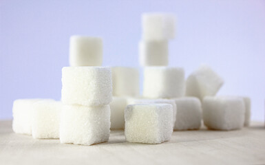 Sugar on a blue background. White sugar cubes on a wooden table.