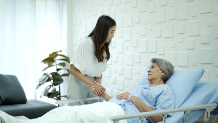 Asian young woman taking care of her mother who resting on the bed in hospital ward. Young woman...