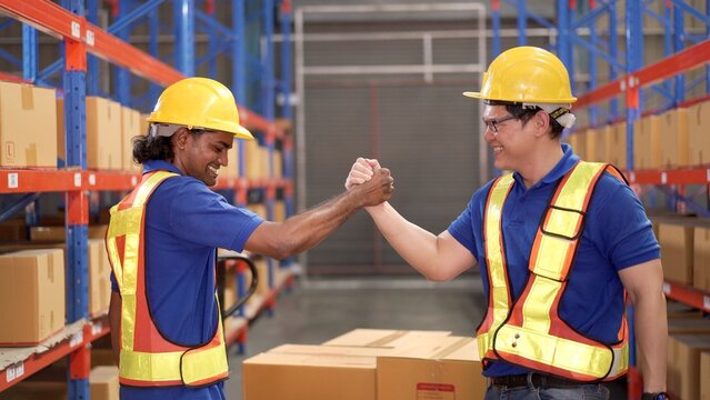 Happy Asian warehouse workers making a hand tagging together and greeting.