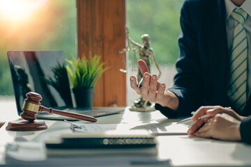 Businessmen and lawyers discuss contract documents with brass scales and judges' hammers on wooden tables in the office. Legal services. Advice. Justice concept.