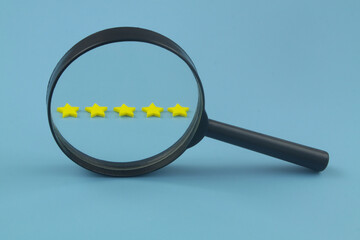 Review rating and feedback concept. Five stars under magnifying glass on blue background with space...