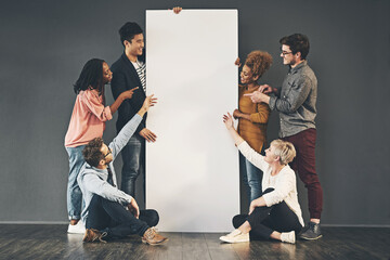 A diverse group of people holding a blank white board or poster and showing advertising copy space....
