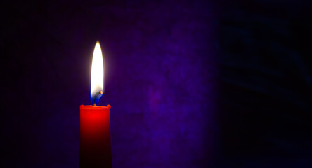 Red candle burning in the dark blue background