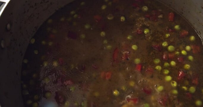 Pouring "Chicha de Jora" into a pot to prepare the Peruvian dish "Arroz con Pato". Close-up.