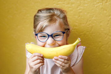 Happy little child girl with yellow banana like smile on yellow background. Preschool girl with...