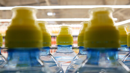 Close-up of many sports plastic bottles of water with yellow caps on a store shelf