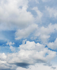 Obraz premium White curly clouds in a blue sky, vertical format