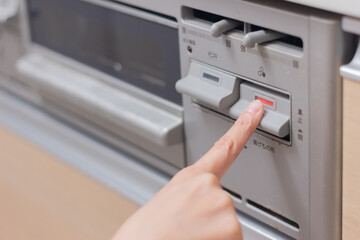 ガスコンロのスイッチを押す女性