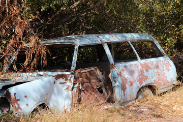 a rusty old car wreck that is slowly falling apart
