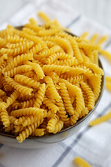 Uncooked dry girandole torsades pasta in a bowl, side view. Close-up.
