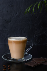 Beans, coffee in glass cup and chocolate on a dark background