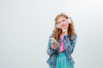 a teenage girl with a backpack in headphones holds a phone on a white background