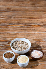Flax and sunflower seeds, salt and sesame on a dark wooden table