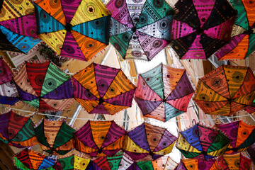 Fototapeta na wymiar Multiple colors umbrellas hanging city street in summer town