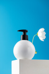 Mockup of a white dispenser with a cosmetic product with a place for your logo on a podium on a blue background.