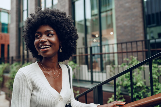 Young smiling african woman poses near stairs in the city