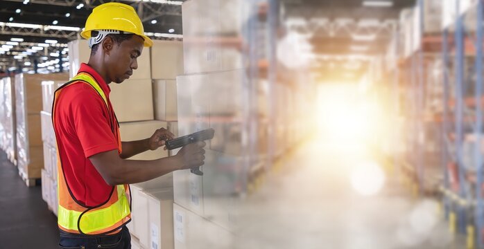 A Man worker scanning package with warehouse barcode scanner in modern storehouse.