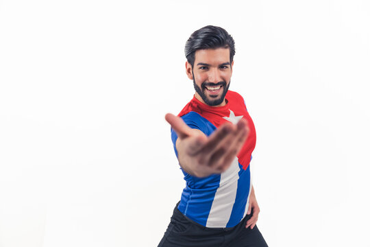 Hispanic man with dark hair and beard wide smile looking into camera wearing puero rico flag t-shirt extended arm inviting to dance. Studio shot. Isolated copy space. High quality photo