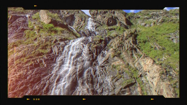 Retro photo camera screen with waterfall scene in mountains, national park of Dombay, Caucasus, Russia. Summer landscape and sunshine weather
