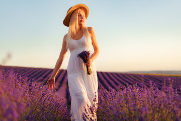 Fototapeta na wymiar Young woman in long white dress standing in lavender field