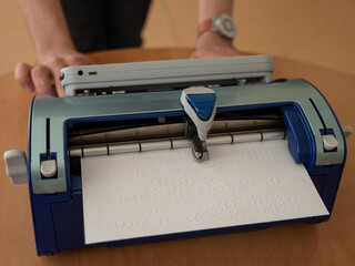 Blind man using braille typewriter. 