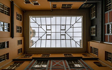 Below view of glass roof from courtyard to old-style brick and orange houses