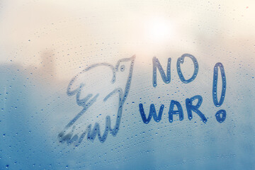 Message call No war and dove of peace bird are painted handwriting on blue window with raindrops