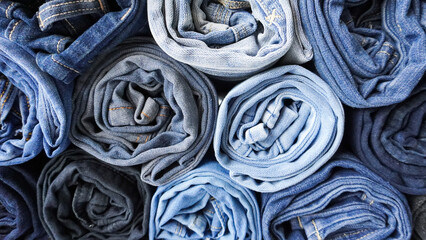 Fototapeta na wymiar Stack of Various Shades of Rolled Up Denim Jeans Background Banner Texture. 