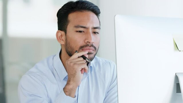 Serious and thinking IT businessman looking at desktop computer writing, working or brainstorming strategy. Smart and intelligent tech manager looking for new solution or ideas for corporate software