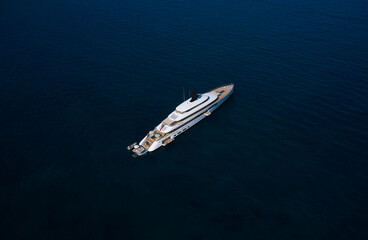 White big yacht at anchor aerial view. Mega yacht on dark water aerial view. Modern big white yacht on the water top view.