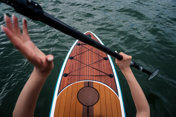 Sports girl on board for glanders surfing. A young slender woman floats on a board with a paddle....