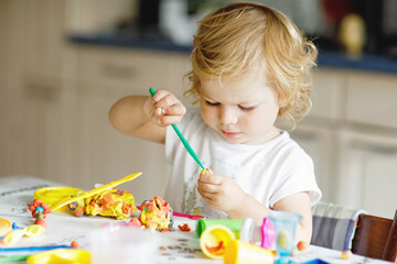 Adorable cute little toddler girl with colorful clay. Healthy baby playing and creating toys from...