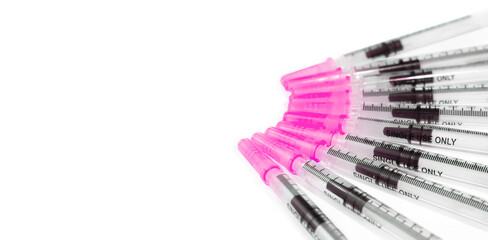 Group of slip tip syringes 1ml, top view. Isolated single use syringes with measuring scale and pink lid. Used to measure and distribute liquid medicine to pets, infants and toddlers. Selective focus.