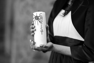 Hands of girl holding candle with crucifix for holy confirmation or communion.