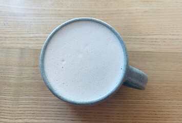 A cup of coffee for breakfast on the natural wooden background, guilty pleasure concept, latte