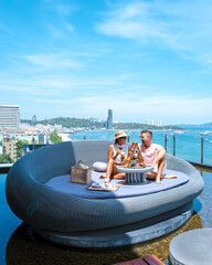 a couple of men and woman having afternoon tea on a rooftop bar in Pattaya Thailand. . a sunny day...