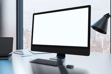 Close up of creative designer desktop with empty mock up computer monitor laptop and supplies in modern office with window and panoramic city view. 3D Rendering.