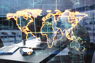Side view of hacker at desktop using computers with abstract glowing golden map hologram on blurry background. Digital world, hacking, malware and technology concept. Double exposure.