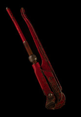 Old red wrench isolated on black background