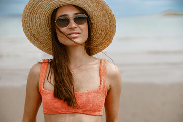 Portrait of beautiful woman in swimsuit standing beach on the background of ocean