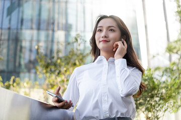 Business women using wireless bluetooth headset outdoors