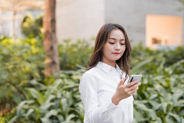 Asian business woman using mobile phone outdoors