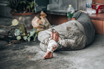 Homeless man sleeps on the street in front of the shop and begging for help and money. Problems of...