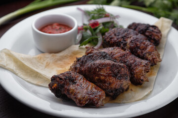 Lamb shish kebab with sauce on a white plate selective focus