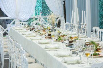 Empty banquet hall ready to receive guests on the summer terrace. white festive table